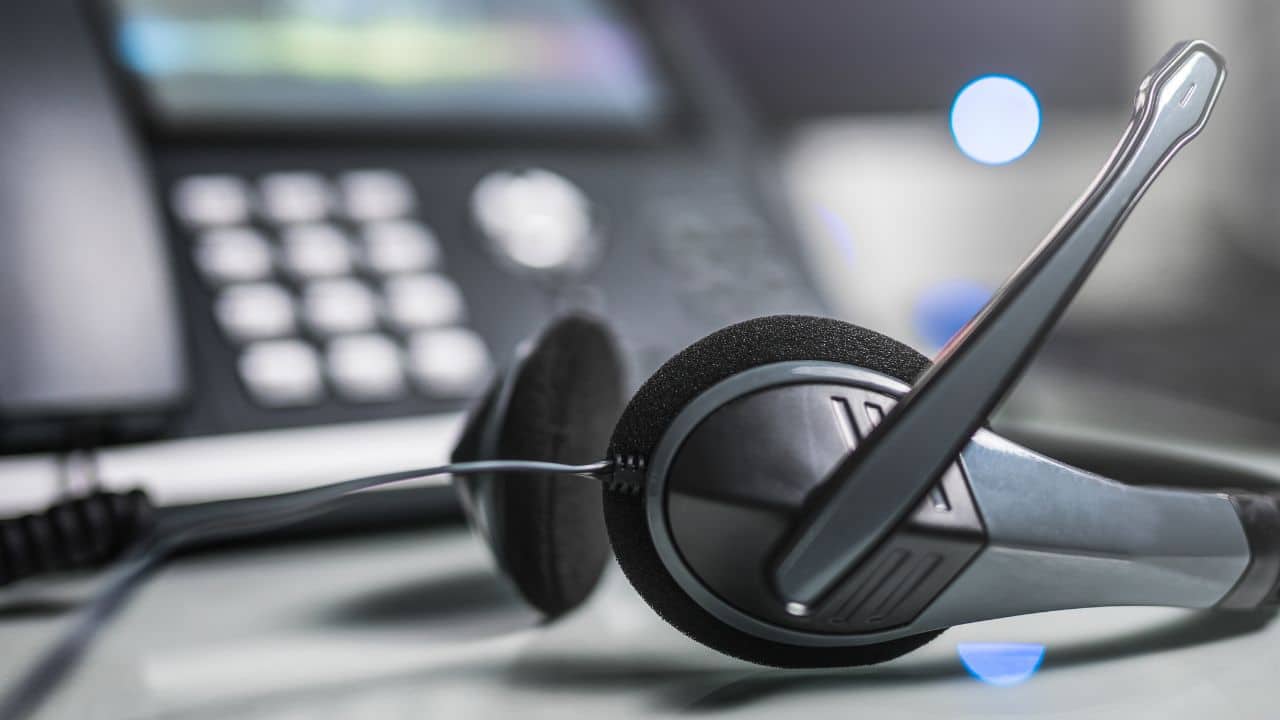 Close-Up Of A Headset With Microphone Next To A Telephone Keypad In A Call Center Or Dealership Bdc Setting. Auto Bdc Headset